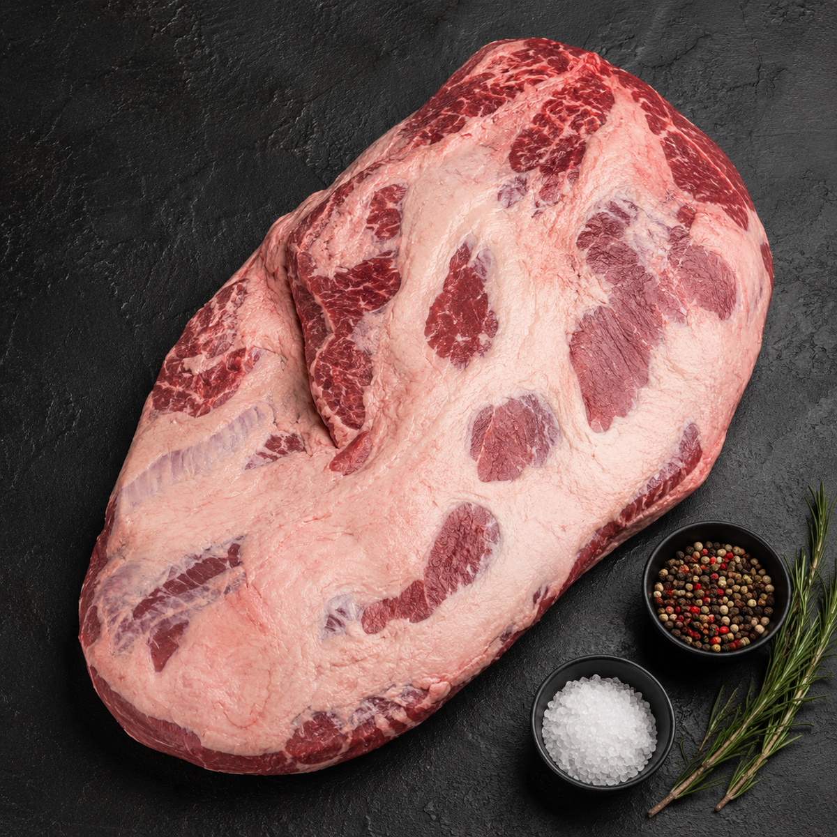Raw beef brisket with spices on a dark surface